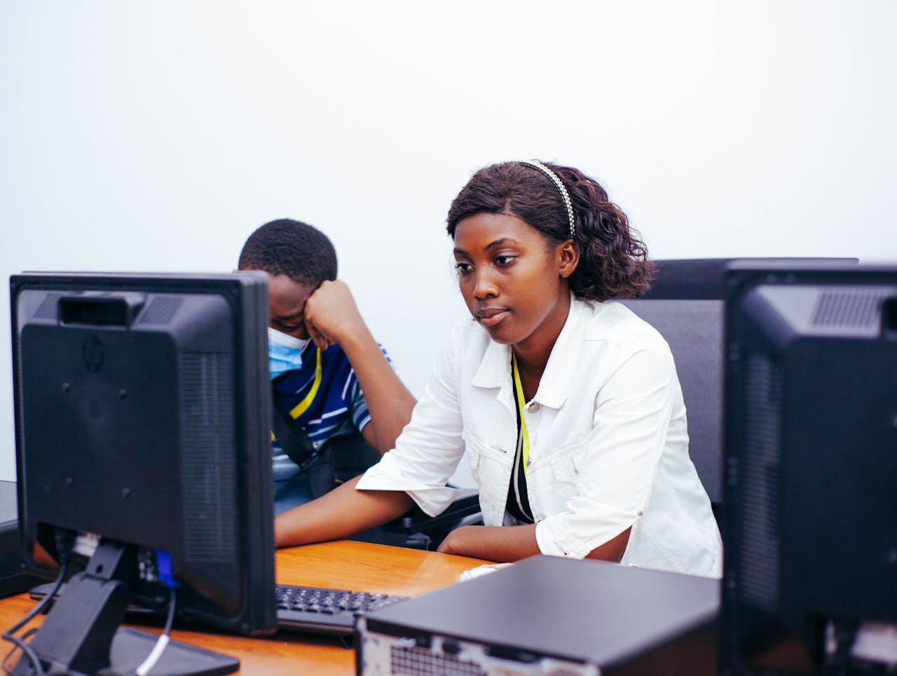 Two young professionals focused on their computer screens, collaborating in a modern office setting.